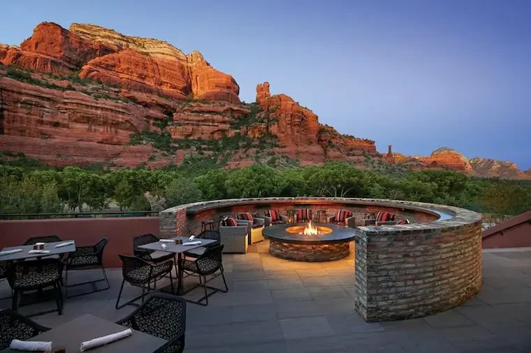 A terrace with seating and a fire pit below red cliffs