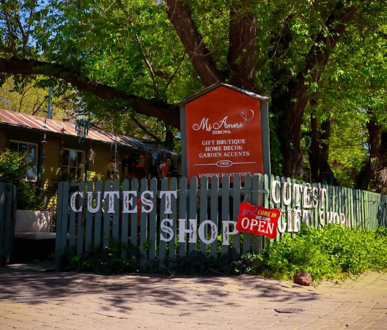 Mi Amoré Sedona's sign and garden gate beneath a large tree