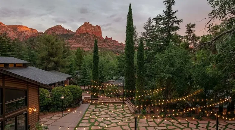 A garden walkway and string lights with red hills in the distance