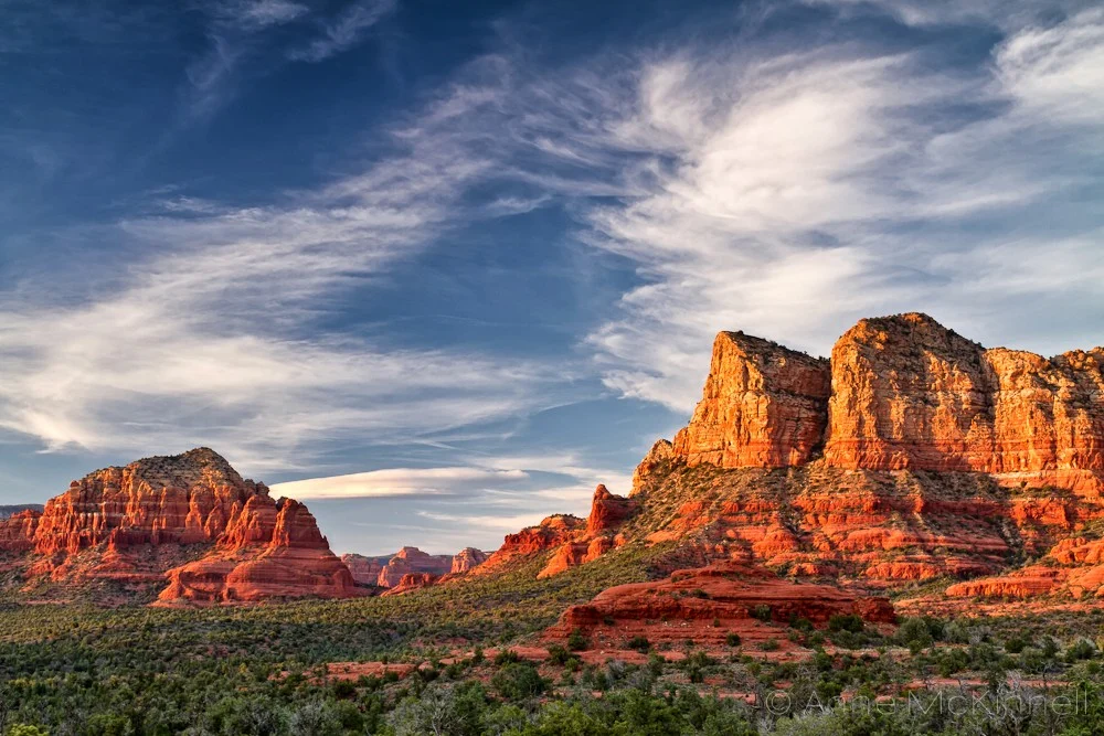 Red sandstone formations under a blue sky with wispy clouds
