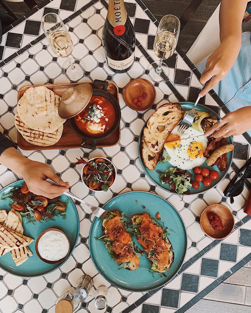 A table filled with shared dishes, drinks, and colorful plates