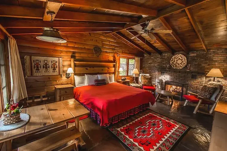 A rustic wood-paneled bedroom with a red bedspread