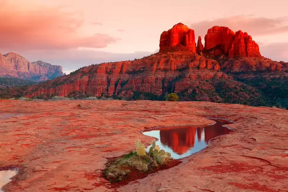 Sunlit red-rock formations reflected in a small rock pool