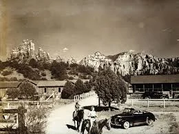 A historical black-and-white street scene with buildings and a parked car